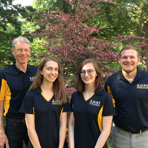 group of four people pose for photo in black polo shirts at The College of ۿ۴ý